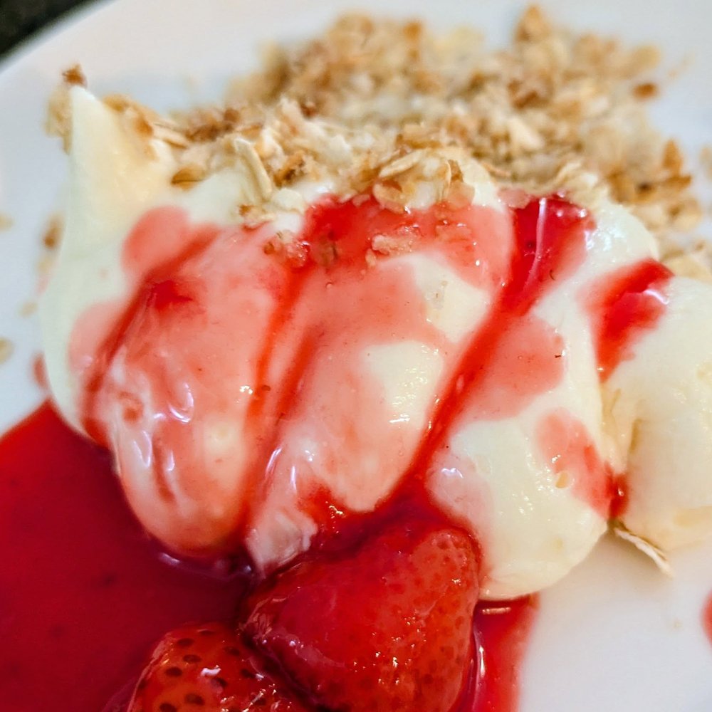 Une pâtisserie nappée de coulis de fraises et parsemée de crumble