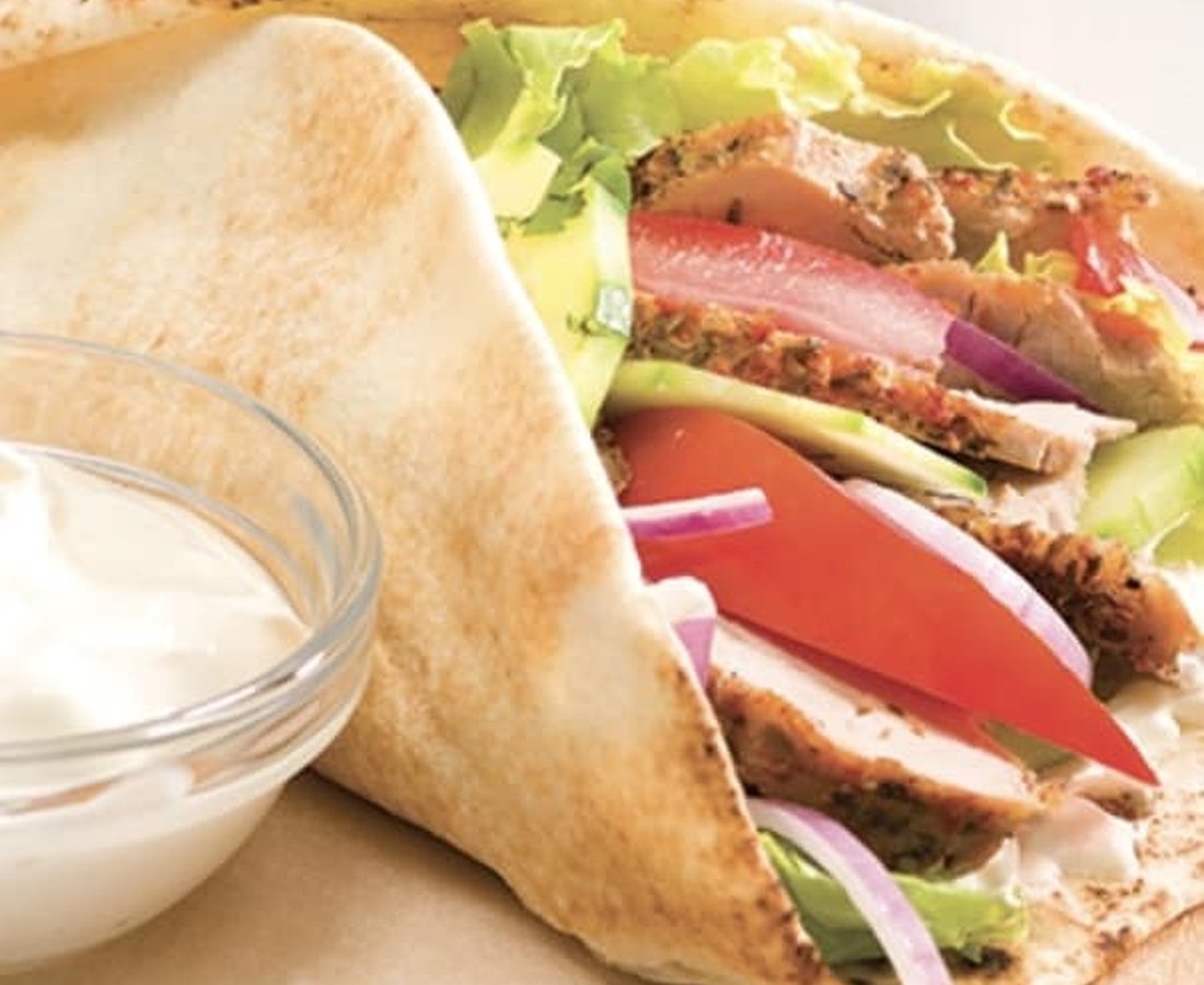 Un wrap garni de poulet, de laitue et de tomate, servi avec sa sauce